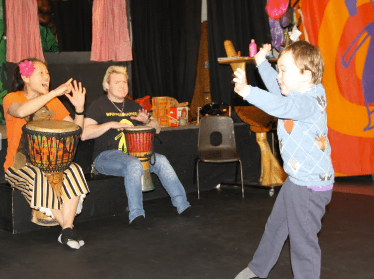Child dancing to tutor playing drum
